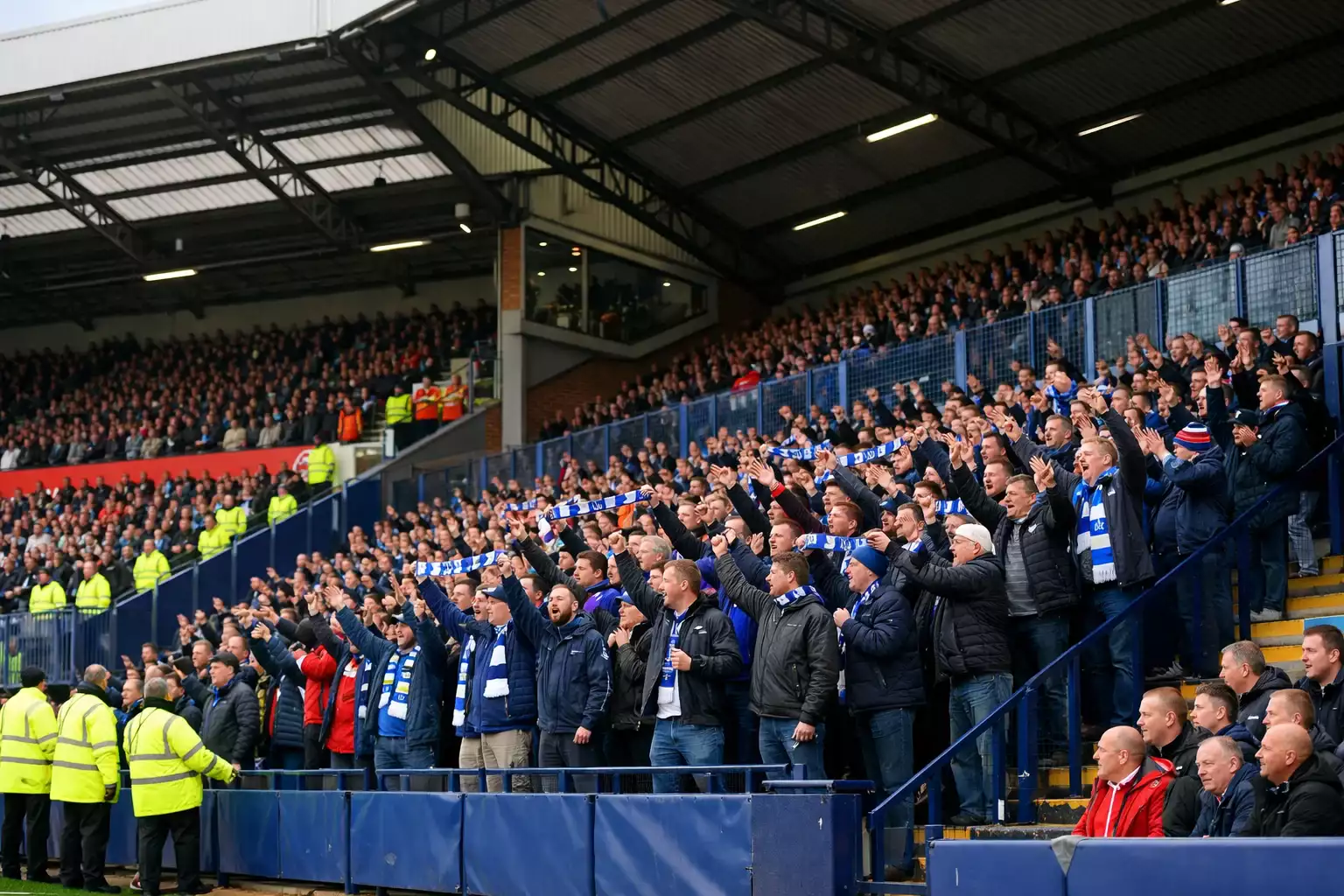 Football away supporters in a dedicated section of a stadium cheering for their team