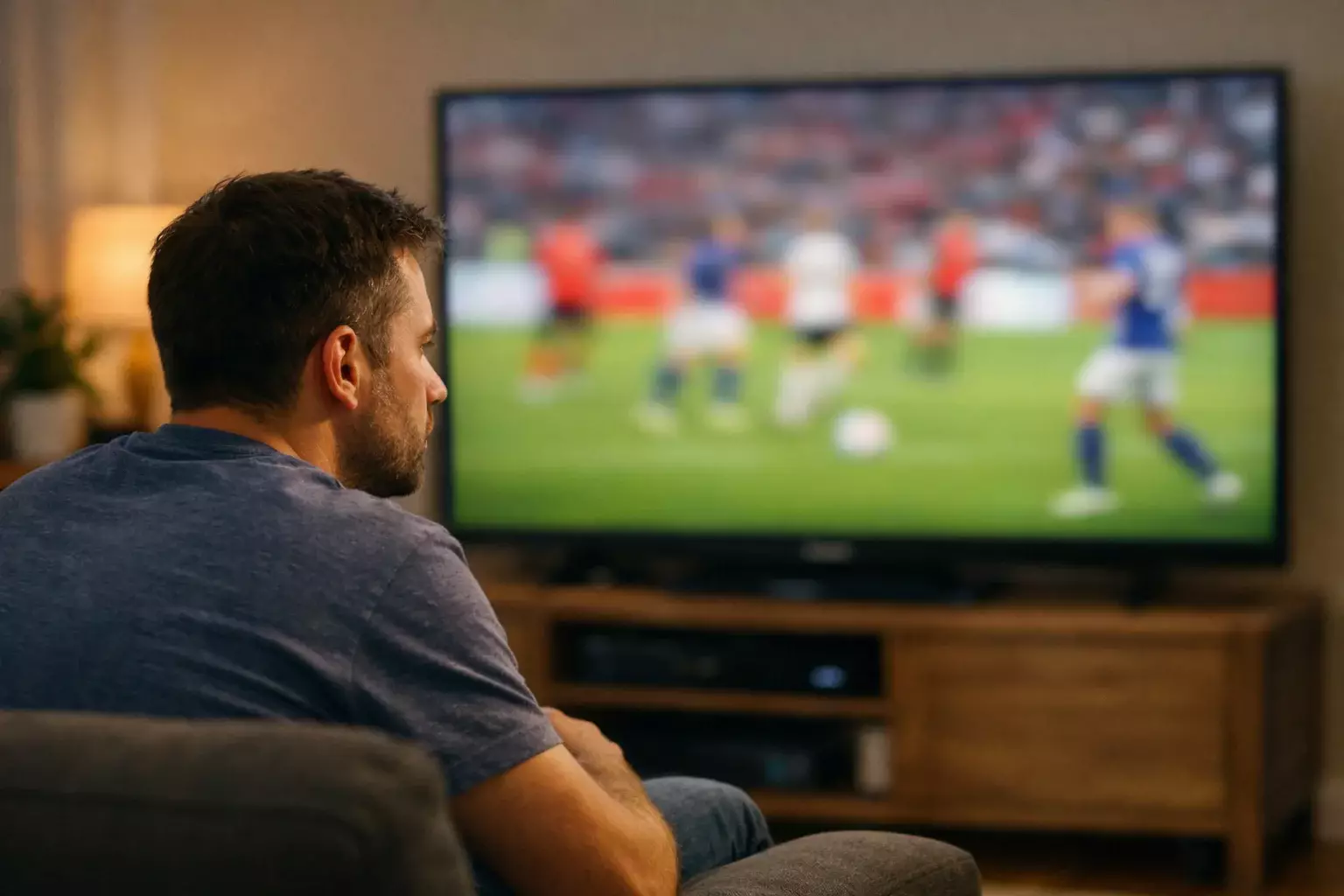 Person intently watching a football match on television at home